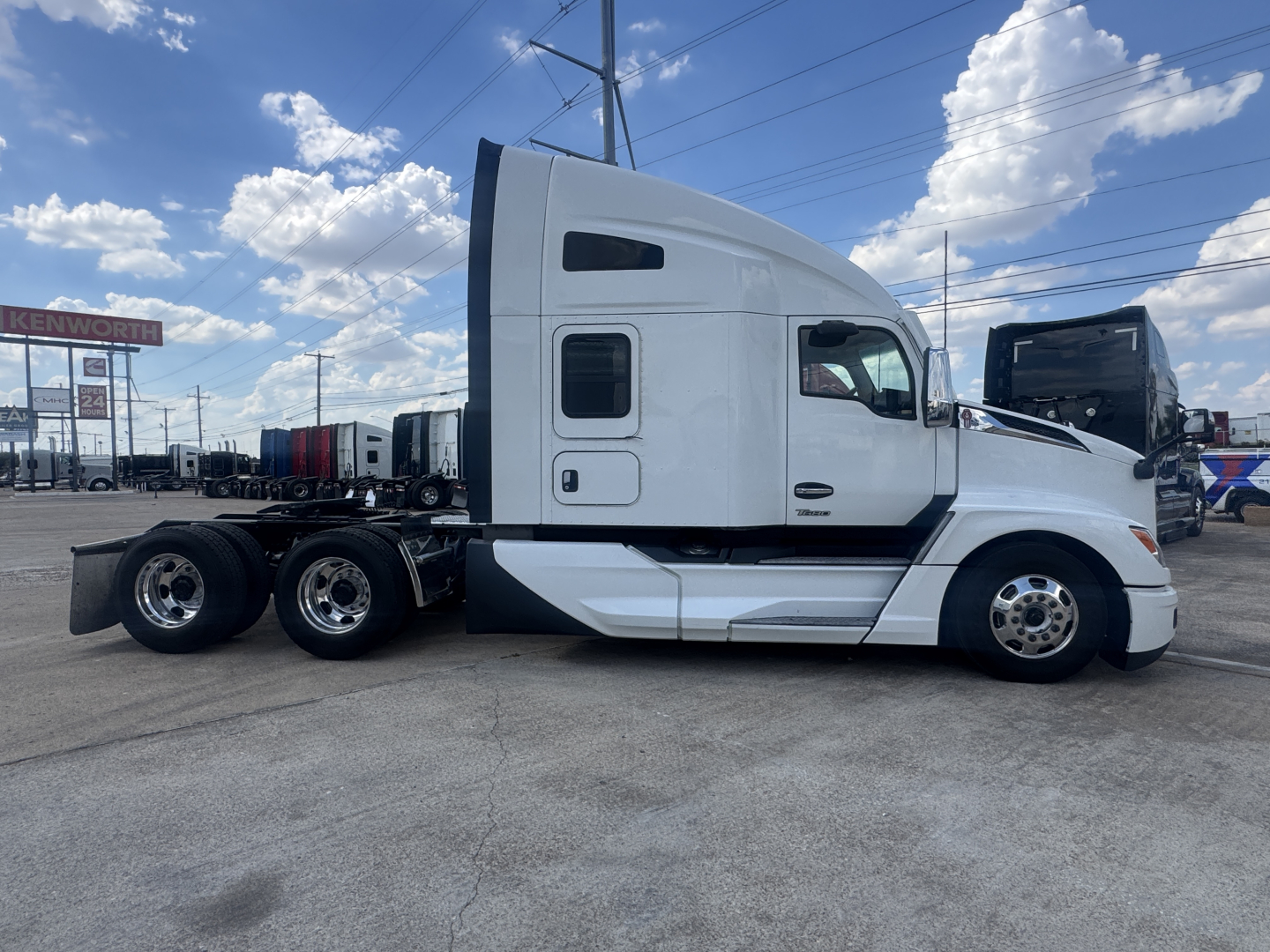 Side view of a white 2023 Kenworth T680 sleeper cab truck with multiple axles at rear, showing cab doors and windows.