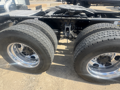 Kenworth T680 chassis showing dual rear axles with large tires and polished steel rims.
