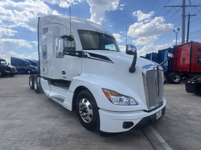 Kenworth T680 conventional sleeper truck in white, front-left view, chrome grille, large side mirrors, daytime running lights, parked in lot.