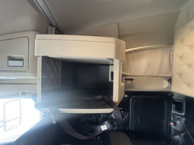 Kenworth T680 sleeper cab interior with open storage compartment and dashboard area visible.
