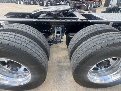Kenworth T680 rear dual-axle setup showing two large tires and wheel rims, hitch/frame area and suspension components visible.