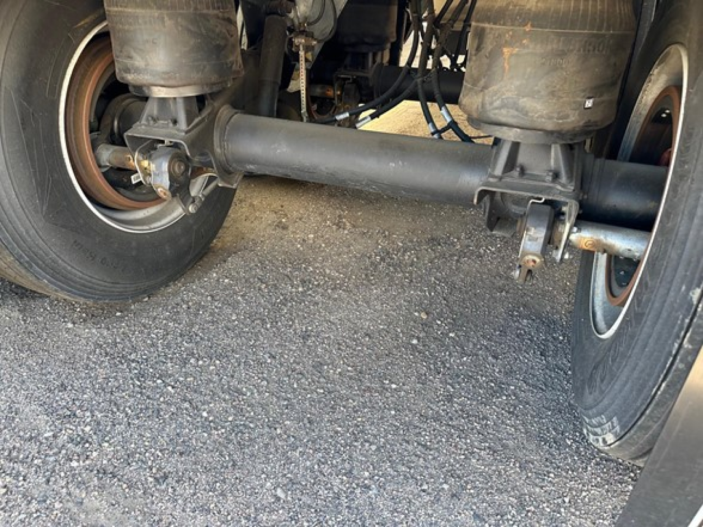 Rear underside of a Stoughton grain trailer showing tandem axles, leaf springs, and drive axle housing.