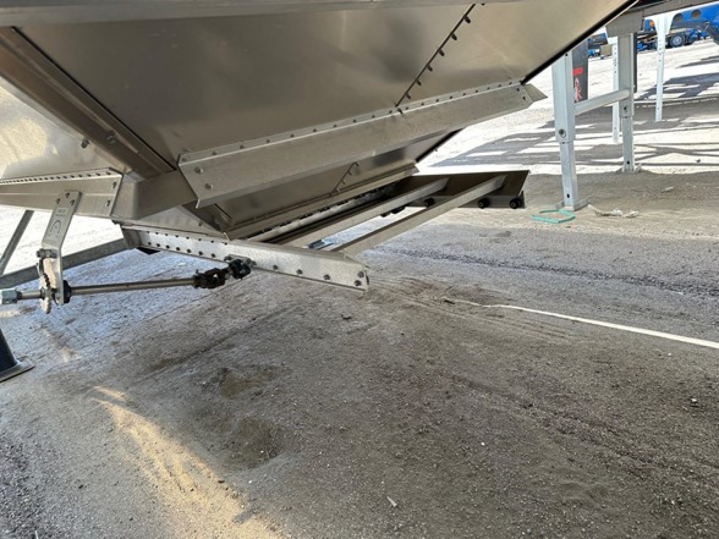 Stoughton Air Ride grain trailer undercarriage showing landing gear and hinge mechanisms with metal hopper edge and support brackets.