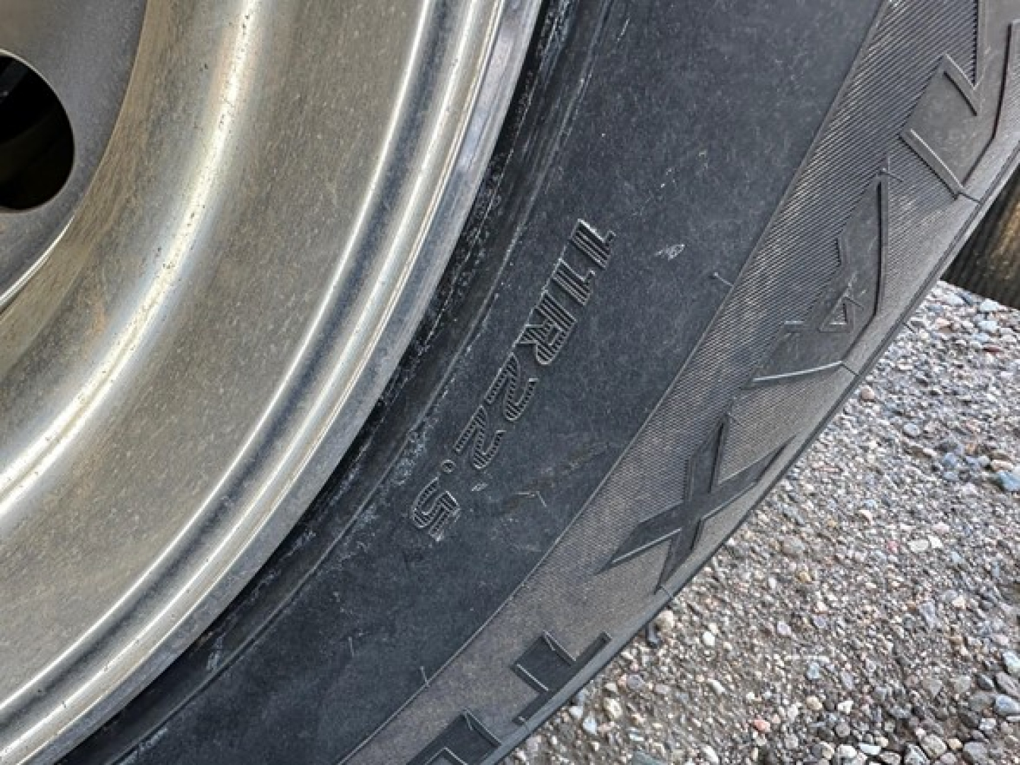 Truck trailer wheel with tire showing tread and sidewall markings, including 'XR' pattern and part of rim.