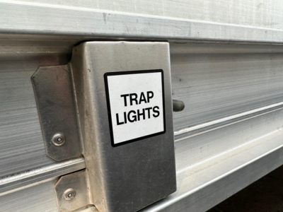 Trailer side with metal box labeled Trap Lights mounted on silver hopper side.
