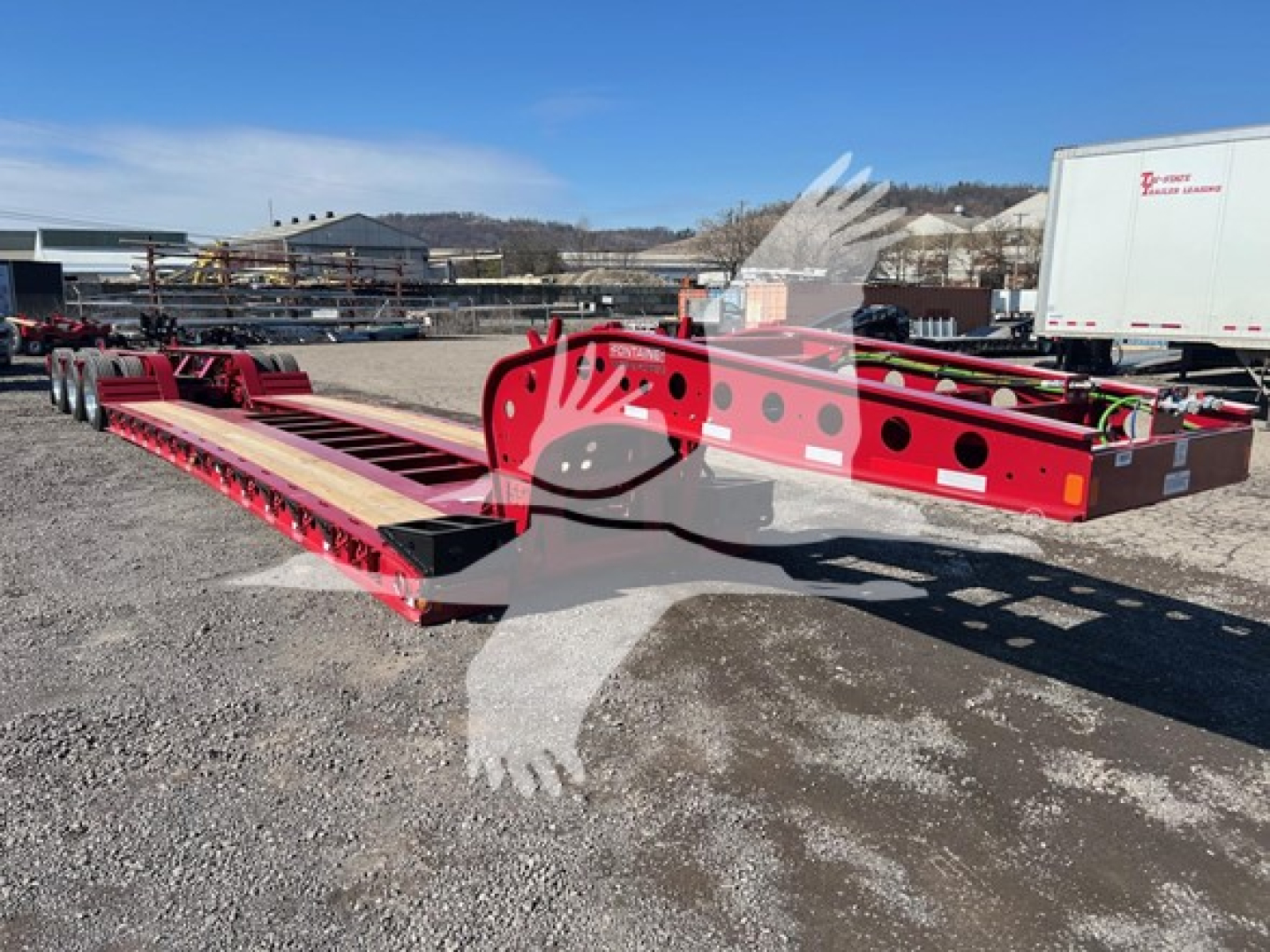 Fontaine 55 Lcc lowboy trailer frame showing red steel structure and axles with exposed mounting holes and wheel hubs.