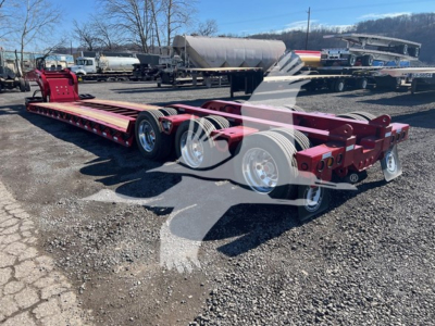 Fontaine lowboy trailer chassis showing multiple axles and red frame with chrome wheels.
