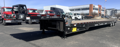 Landoll 440B-53 40 ton traveling axle lowboy trailer in a dealership lot with other trucks in background showing model name and lowboy structure.