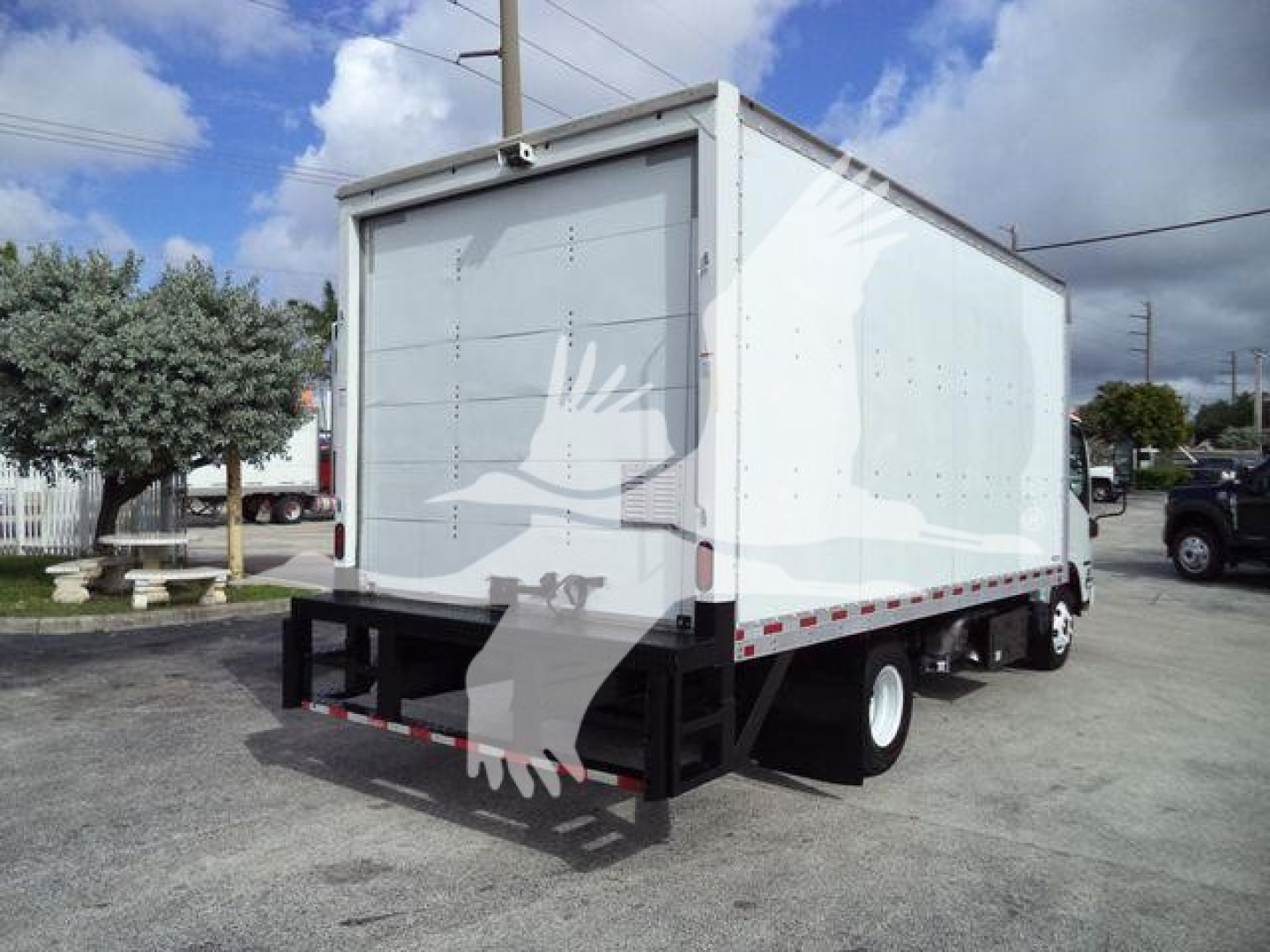 Isuzu NPR-HD box truck rear view showing cargo box, rear doors, and bumper with black safety rails.