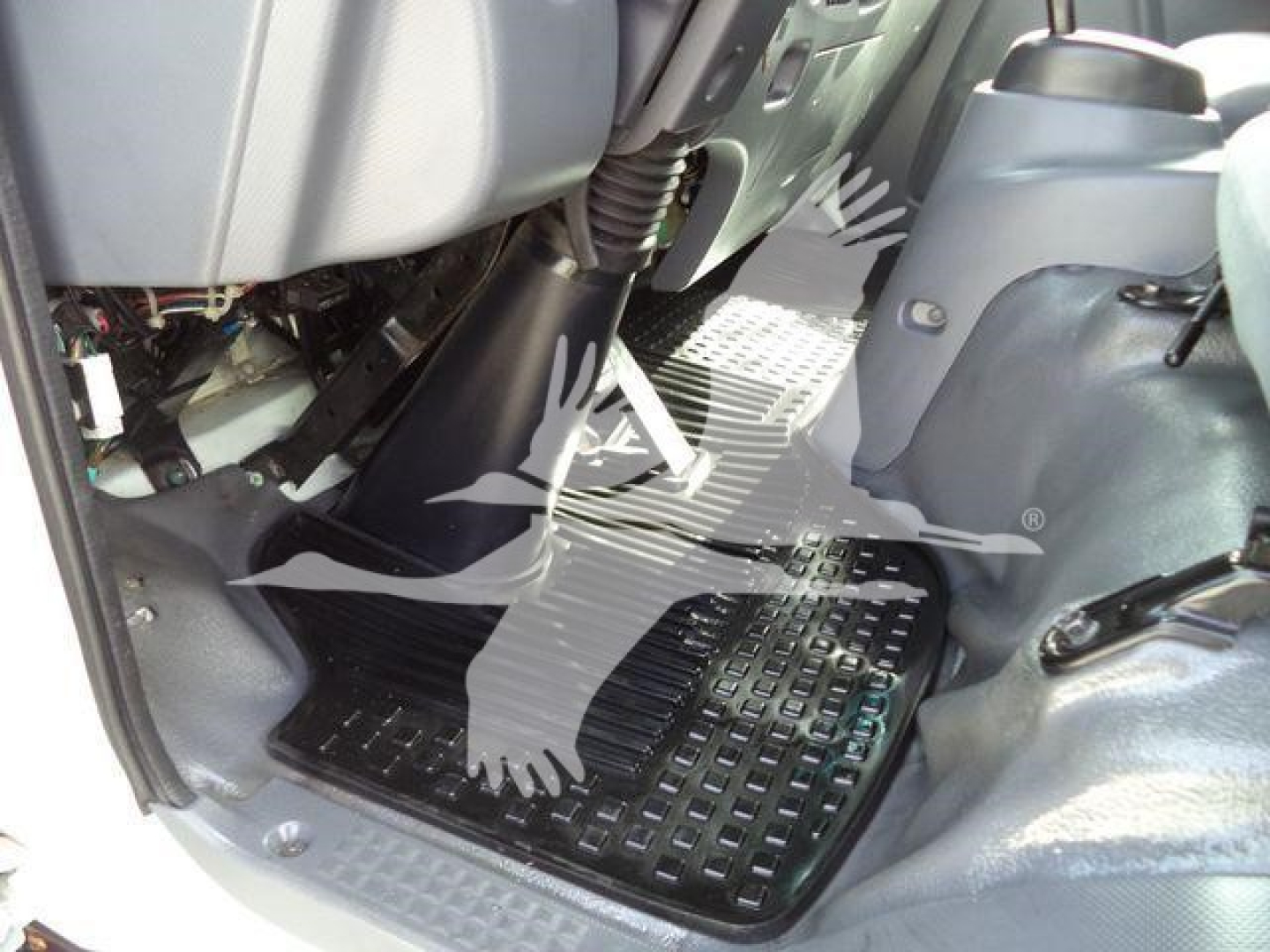 Isuzu NPR HD truck interior view showing driver and passenger footwells with black rubber floor mat and grey plastic panels.