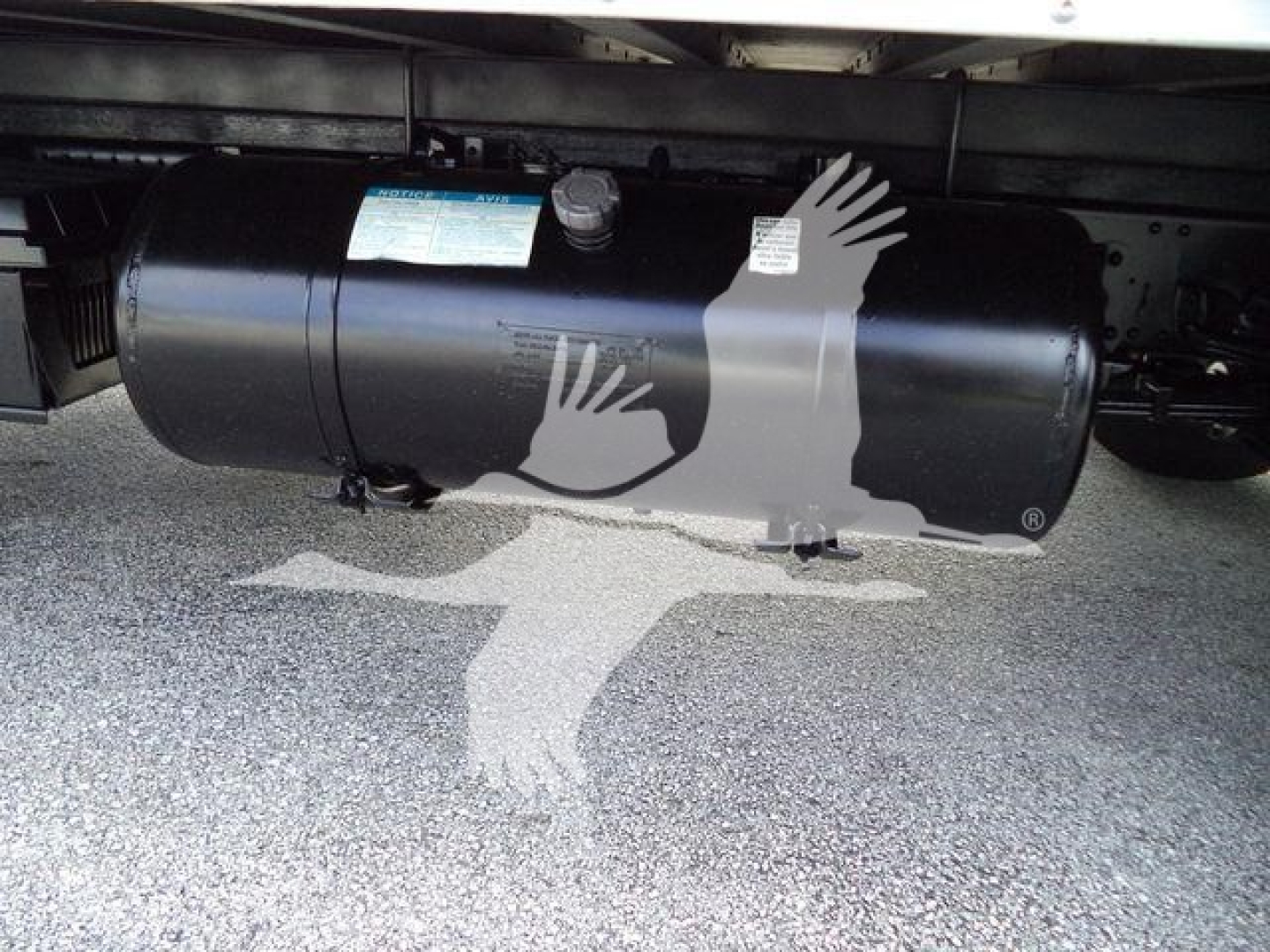 Isuzu NPR HD truck undercarriage showing cylindrical propane or air tank with label and valve.