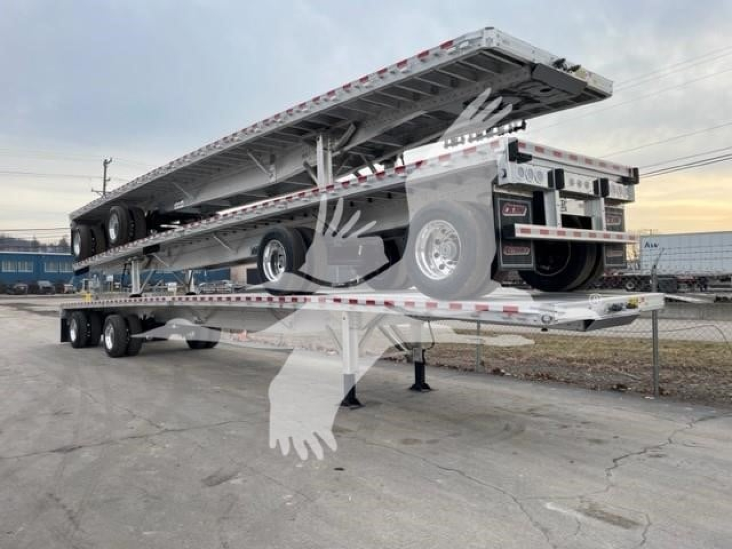 Outline of a flatbed trailer with a raised bed on a multi-axle trailer, rear wheels, and reflective strips; appears to be a Reitnouer CK-100 type trailer.