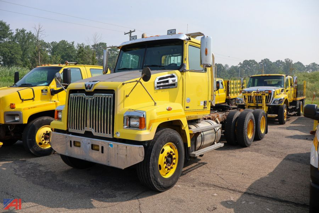 Conventional cab tractor with a bright yellow Western Star 4700 SF in a lineup of trucks.