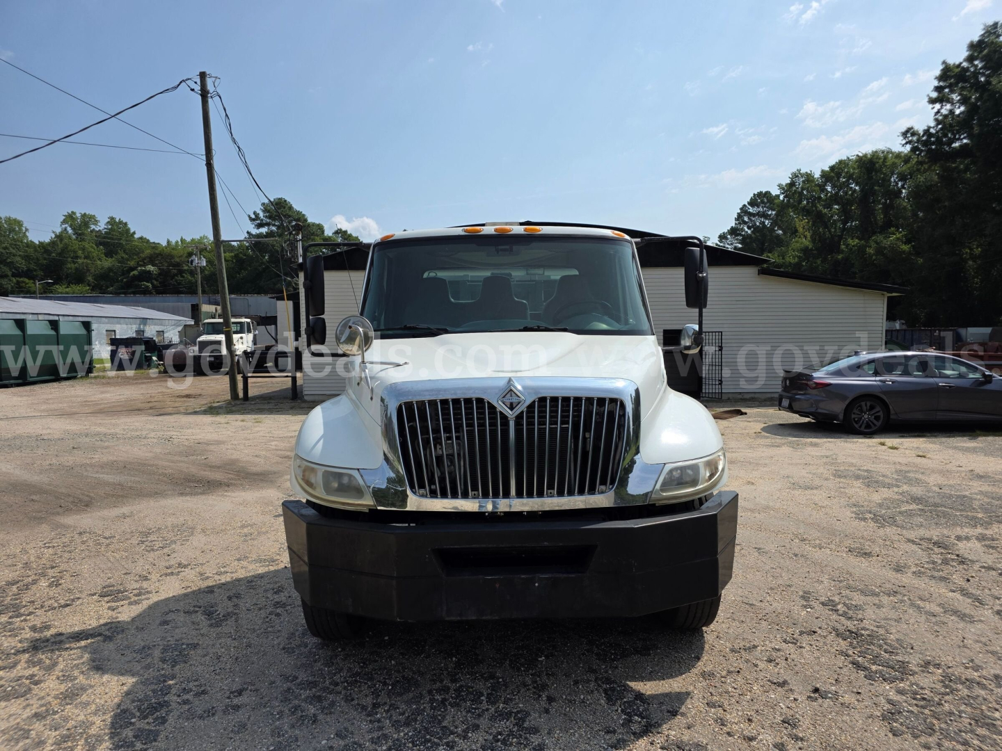Front view of a white 2005 International 4300 DT466 truck with grille and bumper, parked in a lot.