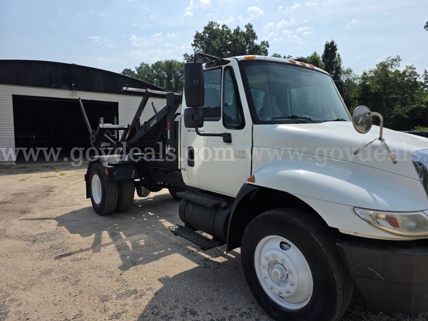 Truck cab and chassis of a 2005 International 4300 DT466, side view, white with black bumper and wheel, flatbed chassis in background.