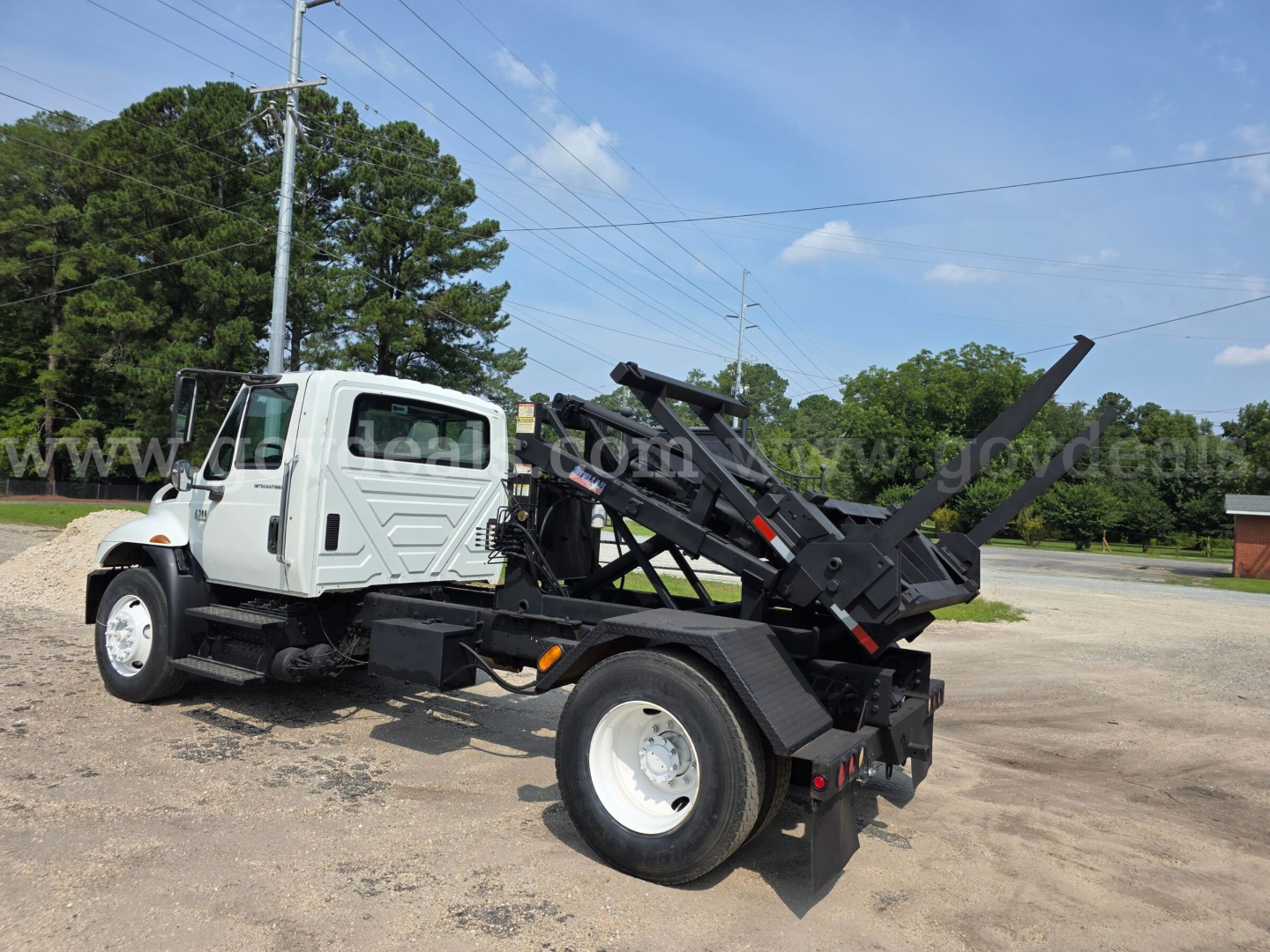 International 4300 dump/haul truck with DT466 engine, white cab, black hydraulic bed, rear loading arm, side view.
