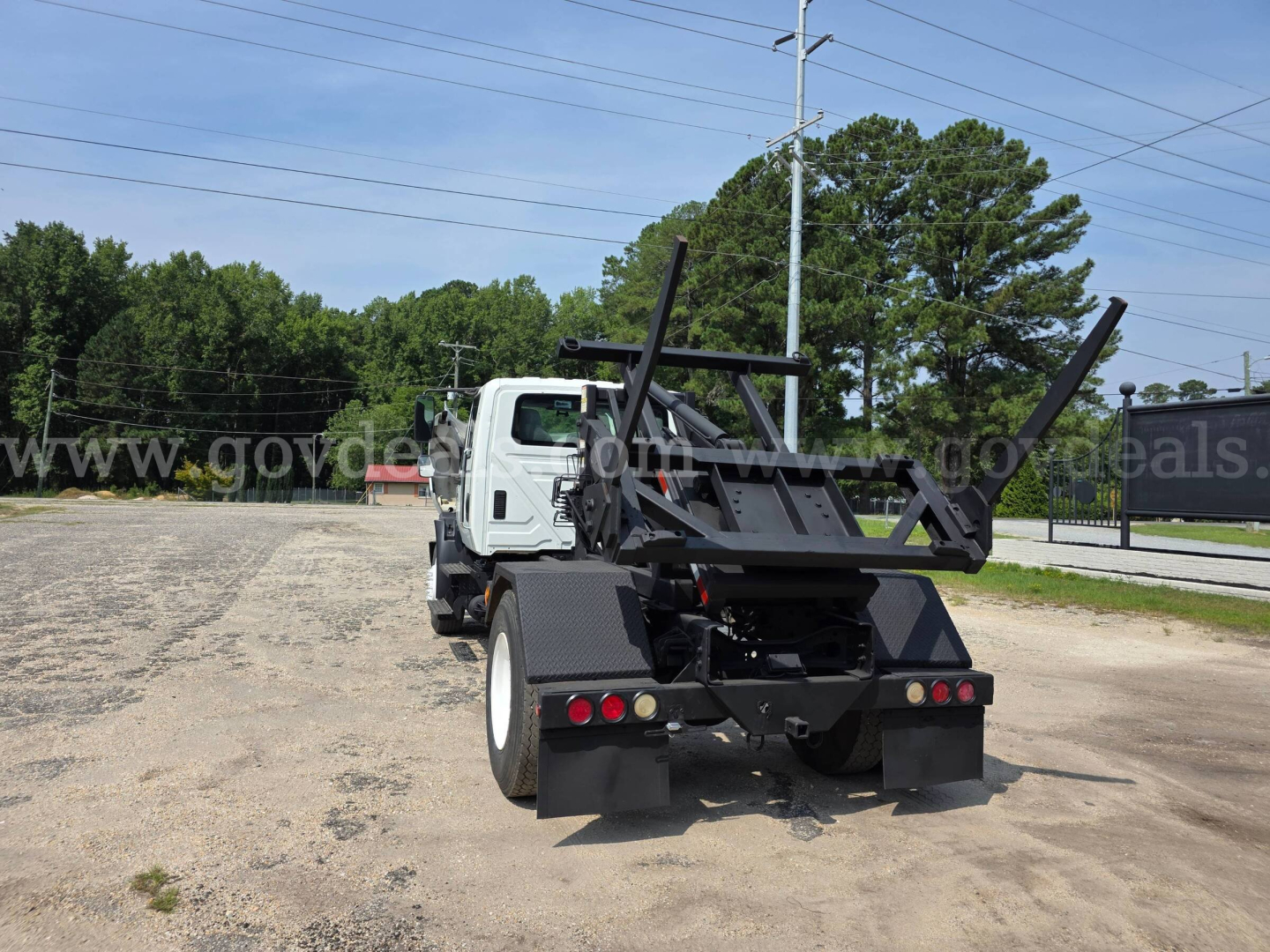 Truck rear view with hydraulic loader and dump body ready for operation.