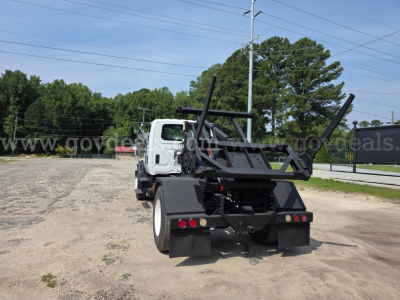 Truck rear view with hydraulic loader and dump body ready for operation.