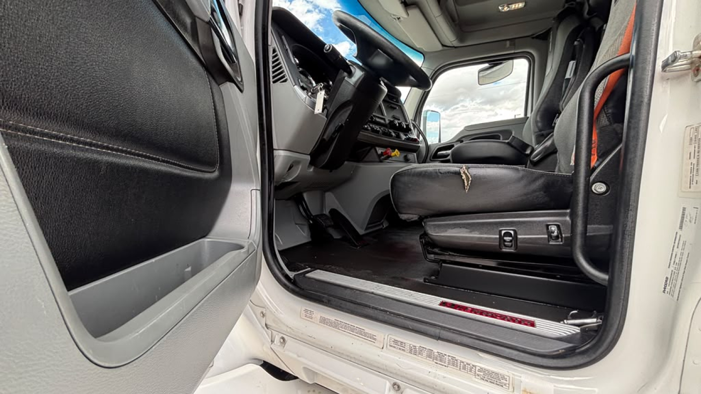 Kenworth T680 cabin entry showing left-hand driver seat and entry step with dashboard, steering wheel, and door panel.