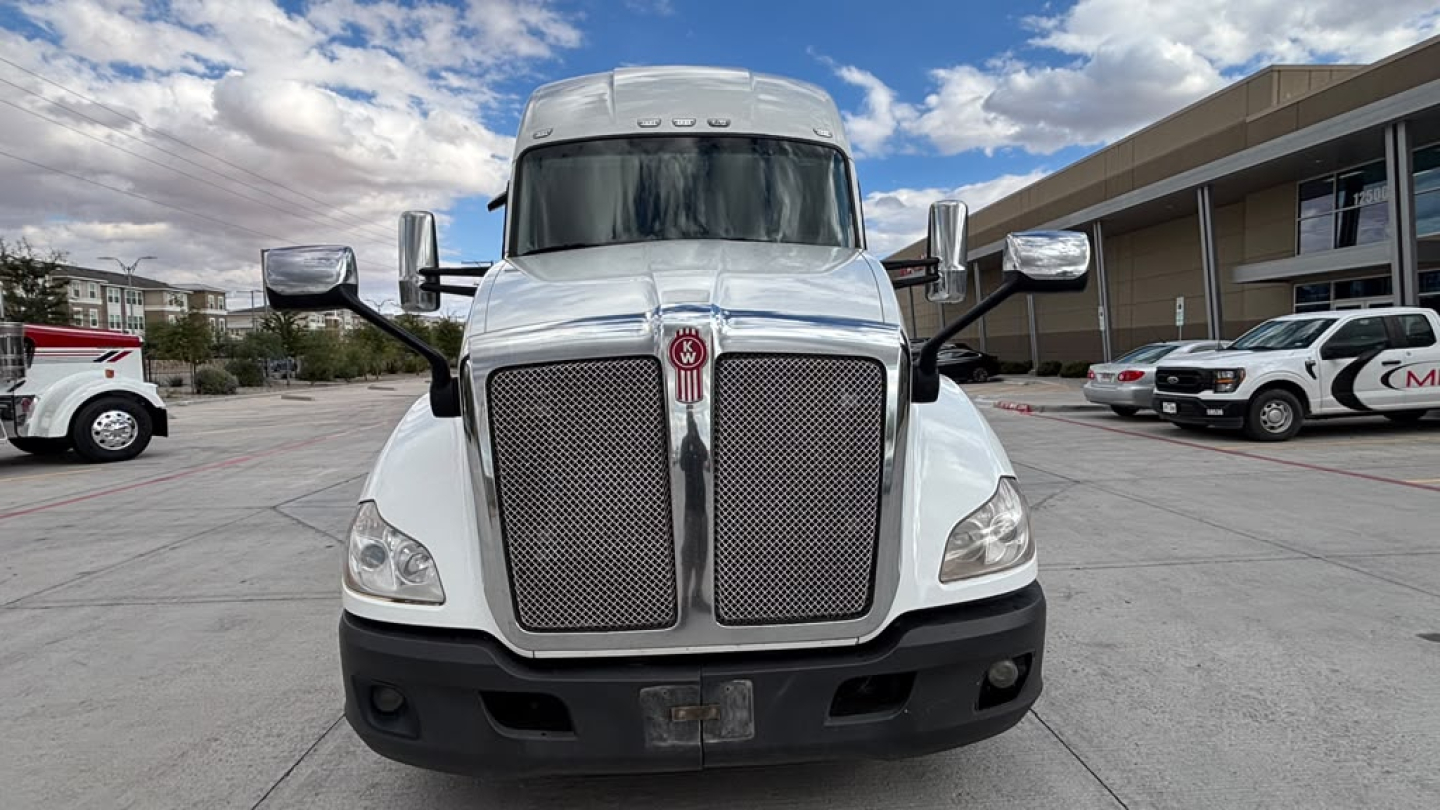Kenworth T680 truck front view showing large chrome grille, dual mirrors, and headlights.