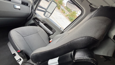 Truck cabin interior seat view showing driver seat and door with window, mirror, and controls.