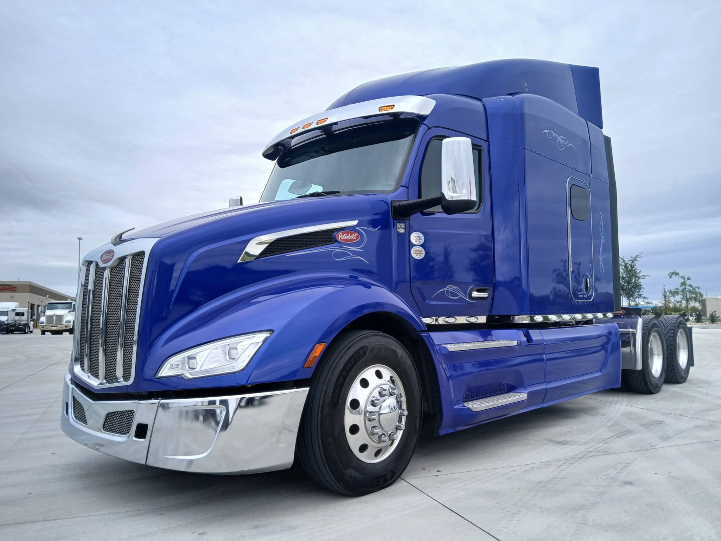 Peterbilt 579 sleeper cab tractor in blue, side view showing front grille, chrome bumper, and dual rear axles.