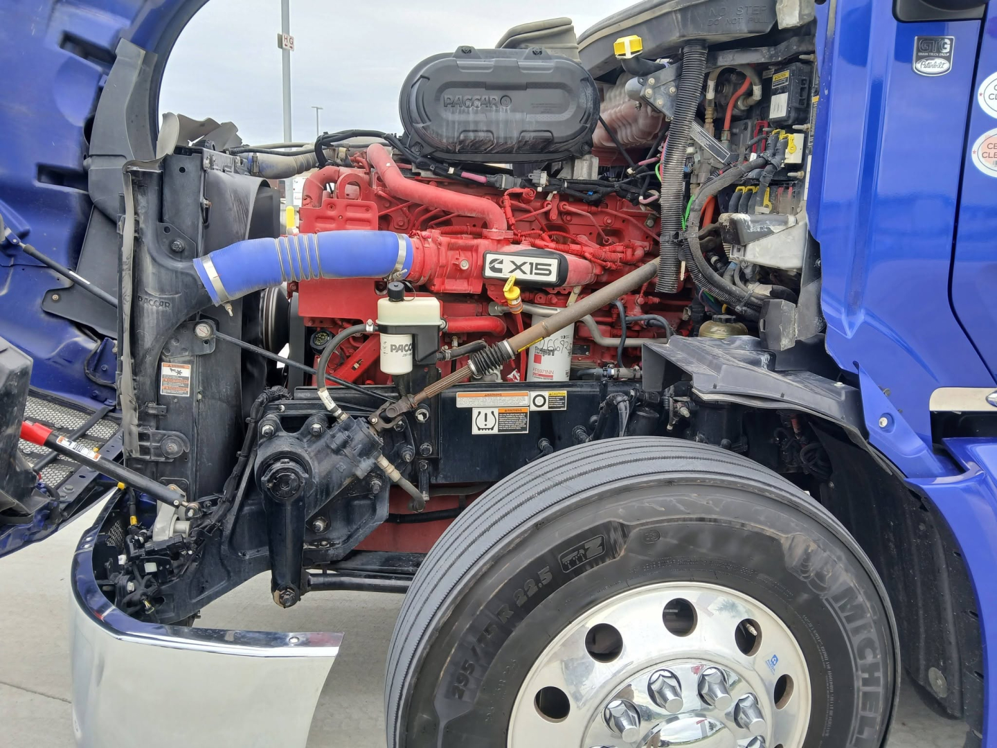 Peterbilt 579 engine bay showing Cummins X15 engine and front left wheel area.