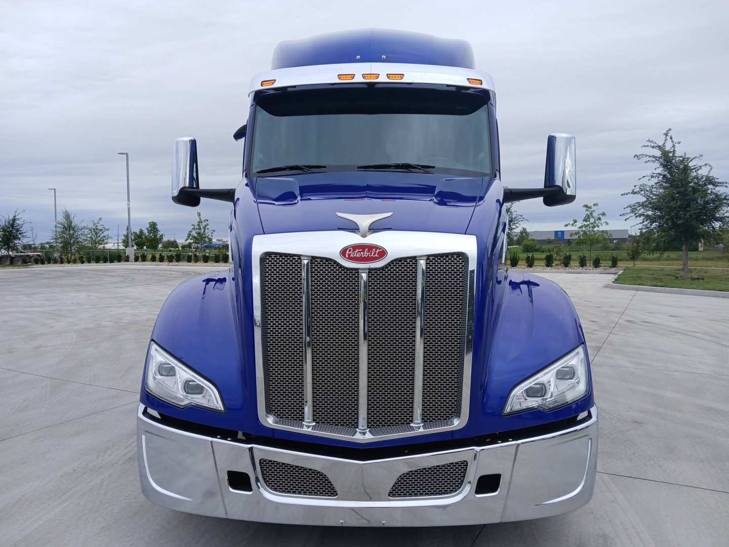 Peterbilt 579 truck front view showing large chrome grille, blue paint, and chrome bumper.