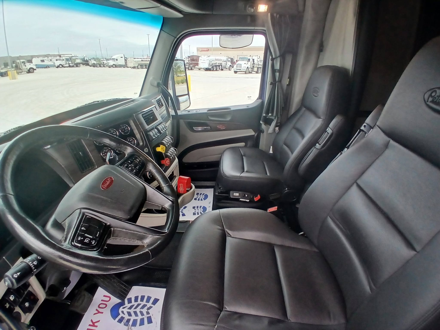 Peterbilt 579 truck interior showing driver and passenger seats, dashboard, steering wheel, and center console.