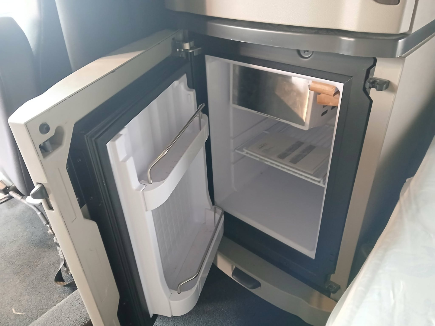Truck cab refrigerator/freezer compartment inside a 2025 Peterbilt 579 sleeper showing open door with interior shelves and freezer section.