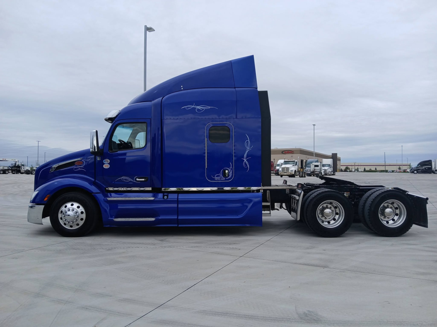 Peterbilt 579 tractor cab side view in blue showing sleeper, wheels, and exhaust area.