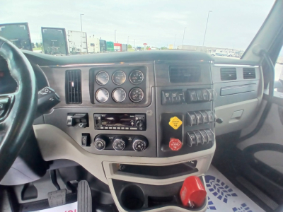 Truck interior dashboard of a Peterbilt 579 showing gauges, control switches, and steering wheel.