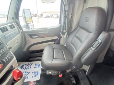 Truck interior seat and dashboard of a Peterbilt 579 cab with driver seat visible, steering wheel area, window, and controls.
