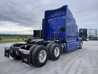 Peterbilt 579 tractor rear view showing sleeper cab, blue exterior, dual rear axles, fifth wheel, and mud flaps.