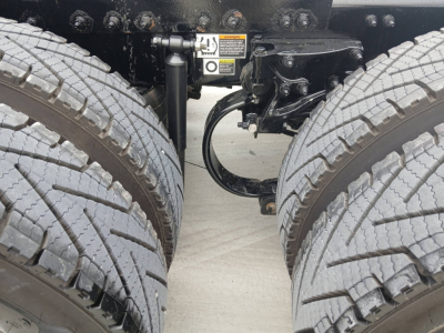 Peterbilt 579 truck dual rear tires with chassis and suspension components visible between wheels; warning sticker and hydraulic lines near the frame.