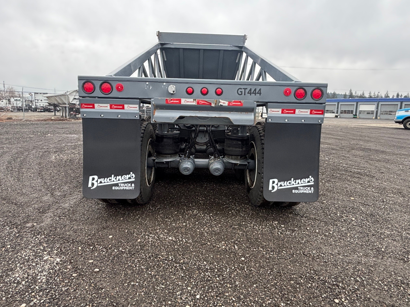 Dump trailer rear showing taillights, bumper, mud flaps with 'Bruckners' logos, dual axles, and license-plate area. Text includes 'GT444' on crossbar and 'Bruckners' on mud flaps.
