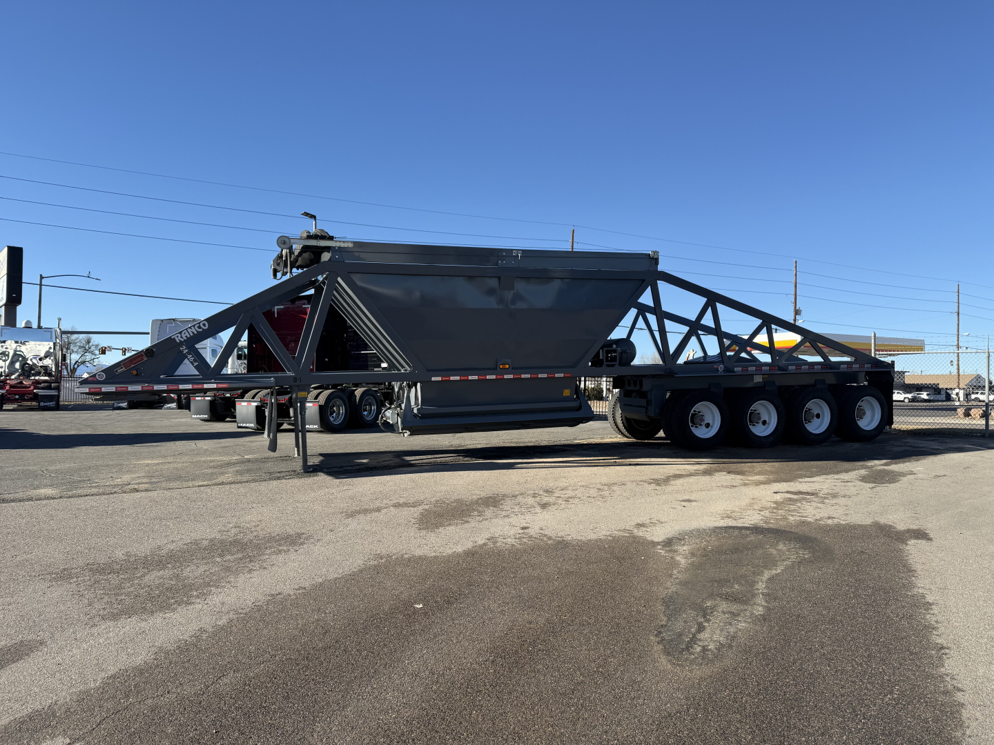 Dump trailer in-service with triangular frame and three-axle configuration showing Ranco LW24464 model text on side.