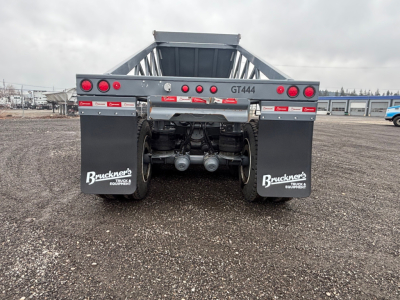 Dump trailer rear showing taillights, bumper, mud flaps with 'Bruckners' logos, dual axles, and license-plate area. Text includes 'GT444' on crossbar and 'Bruckners' on mud flaps.