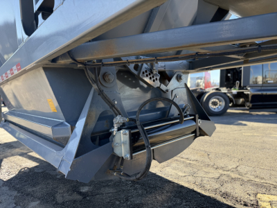 Dump trailer side showing hydraulic hose assembly and undercarriage with winch and frame components, part of Ranco LW24464 trailer model.
