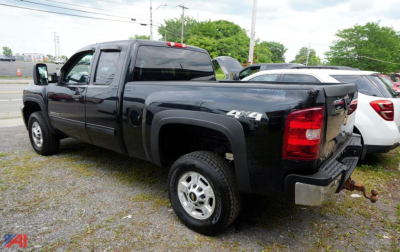 Pickup truck showing rear and passenger side of a black 2013 Chevrolet 2500HD Silverado Ext Cab 4x4 with hitch in a parking lot.