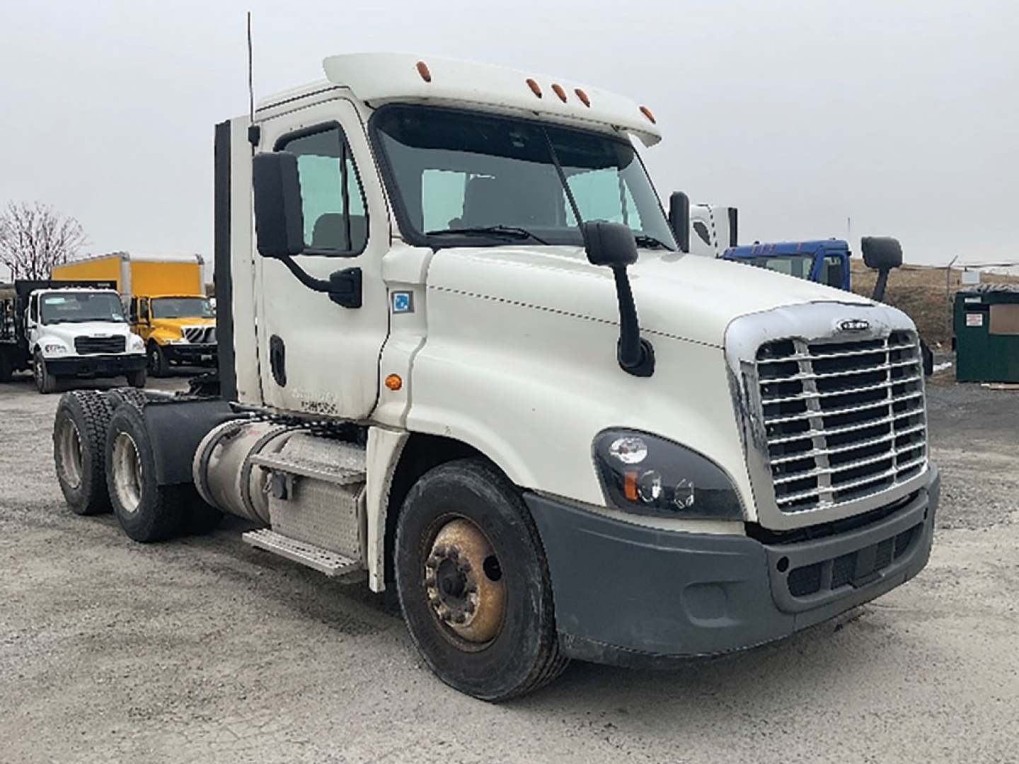 Freightliner Cascadia125 tractor cab side view showing front grille, headlights, large side mirrors, two fuel tanks, and wheels.