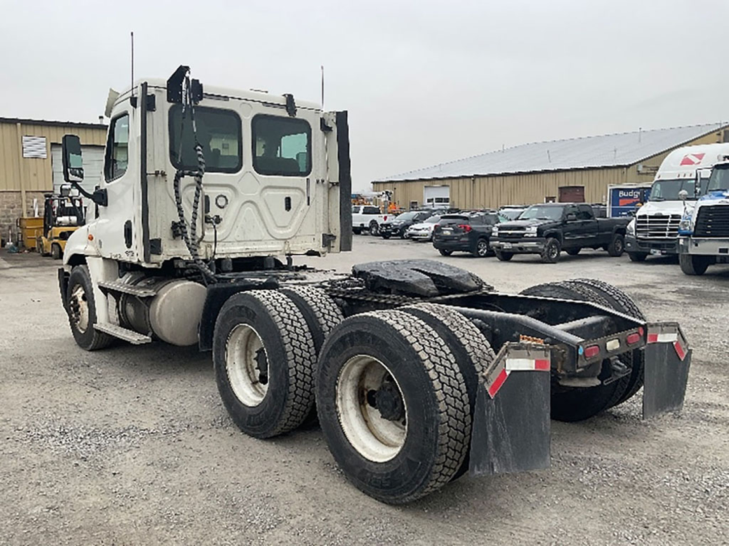 Truck chassis rear view showing tandem axle configuration with dual rear wheels, mud flaps, and fifth wheel area visible.