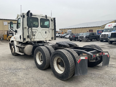 Truck chassis rear view showing tandem axle configuration with dual rear wheels, mud flaps, and fifth wheel area visible.