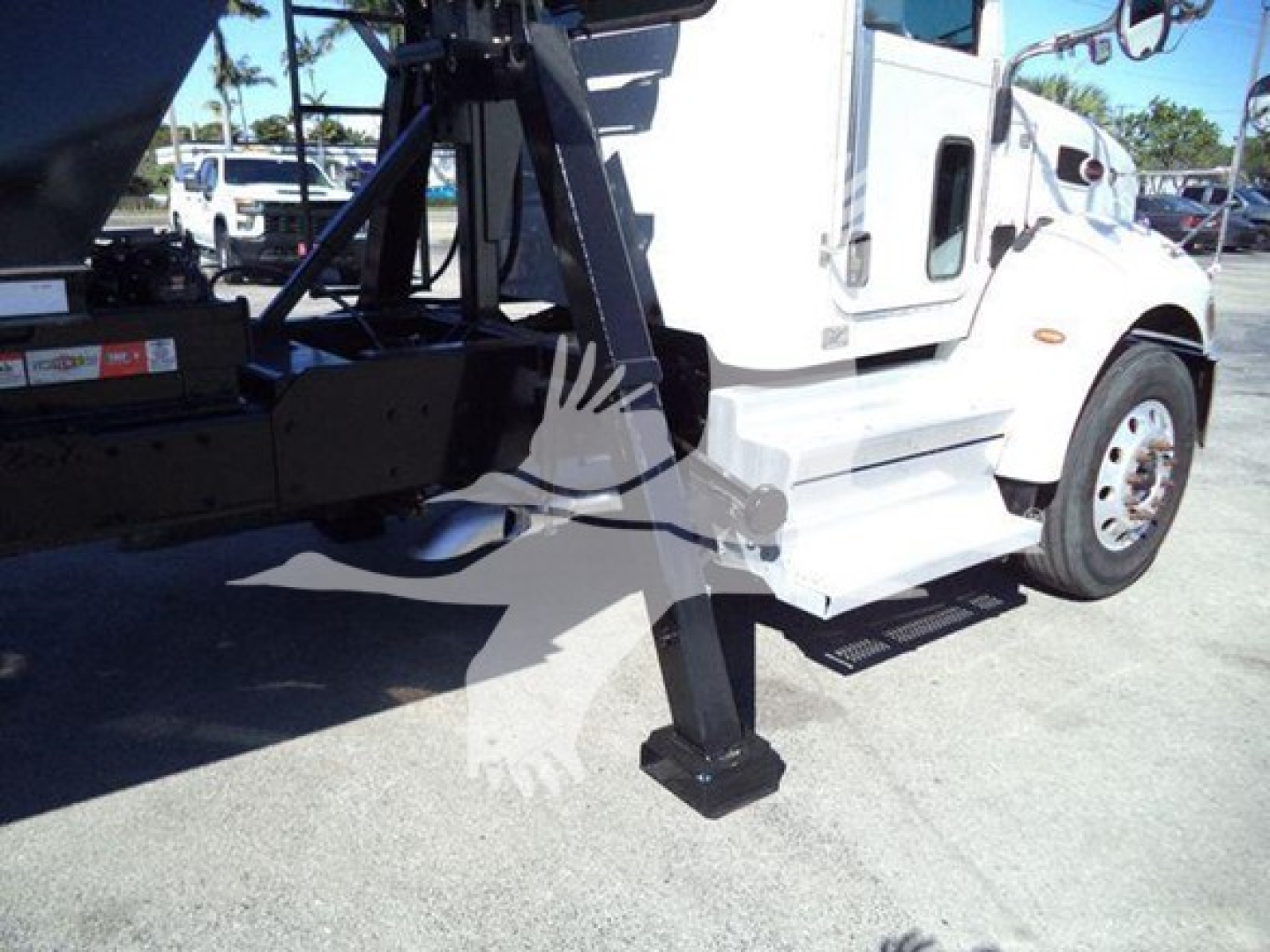 Truck side view showing a blue wheel lift and hitch near the front wheel of a white Peterbilt 337 with a black stand and step plate.