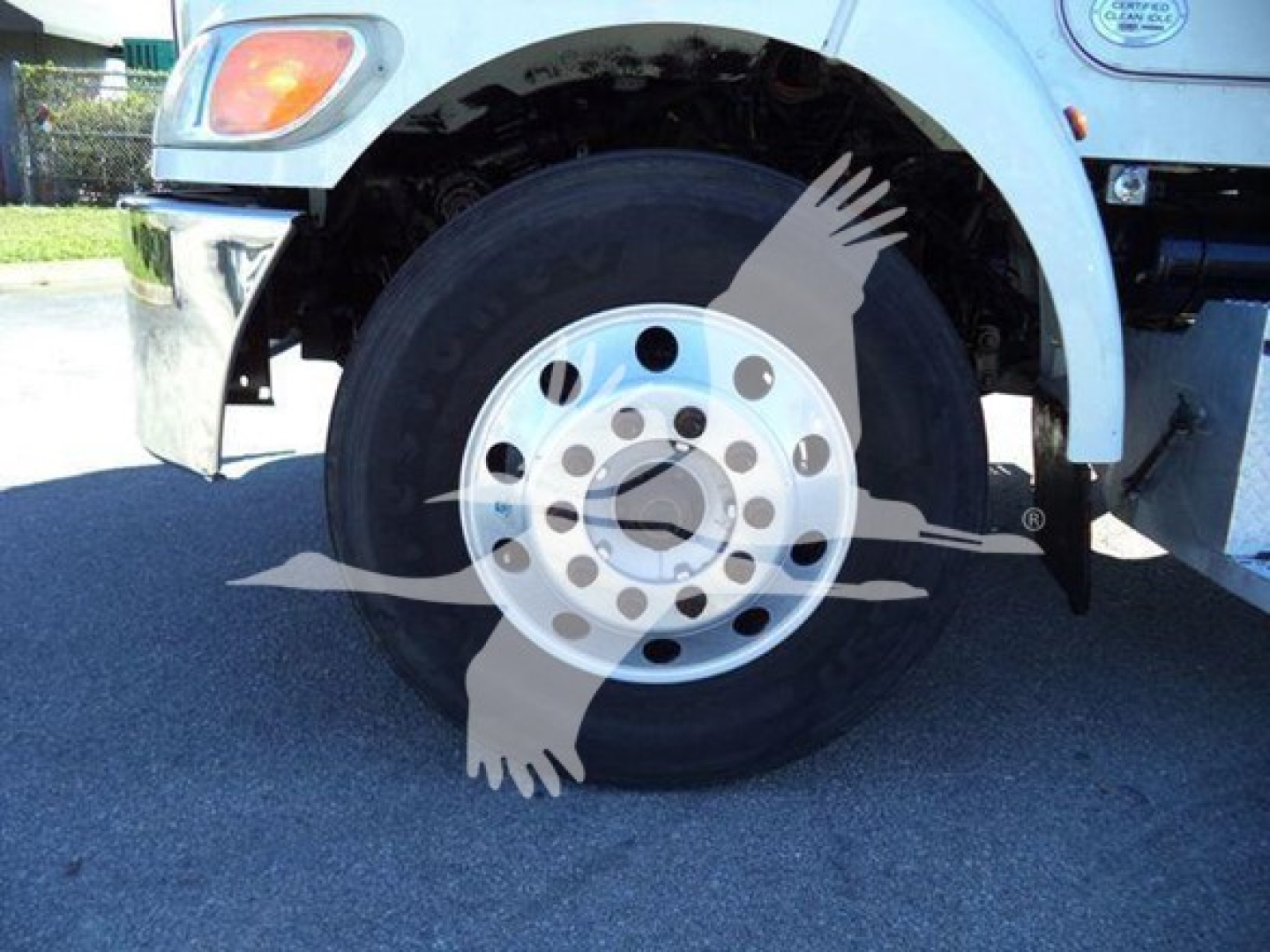 Front wheel of a Peterbilt truck showing a silver steel rim with circular holes and a black tire.