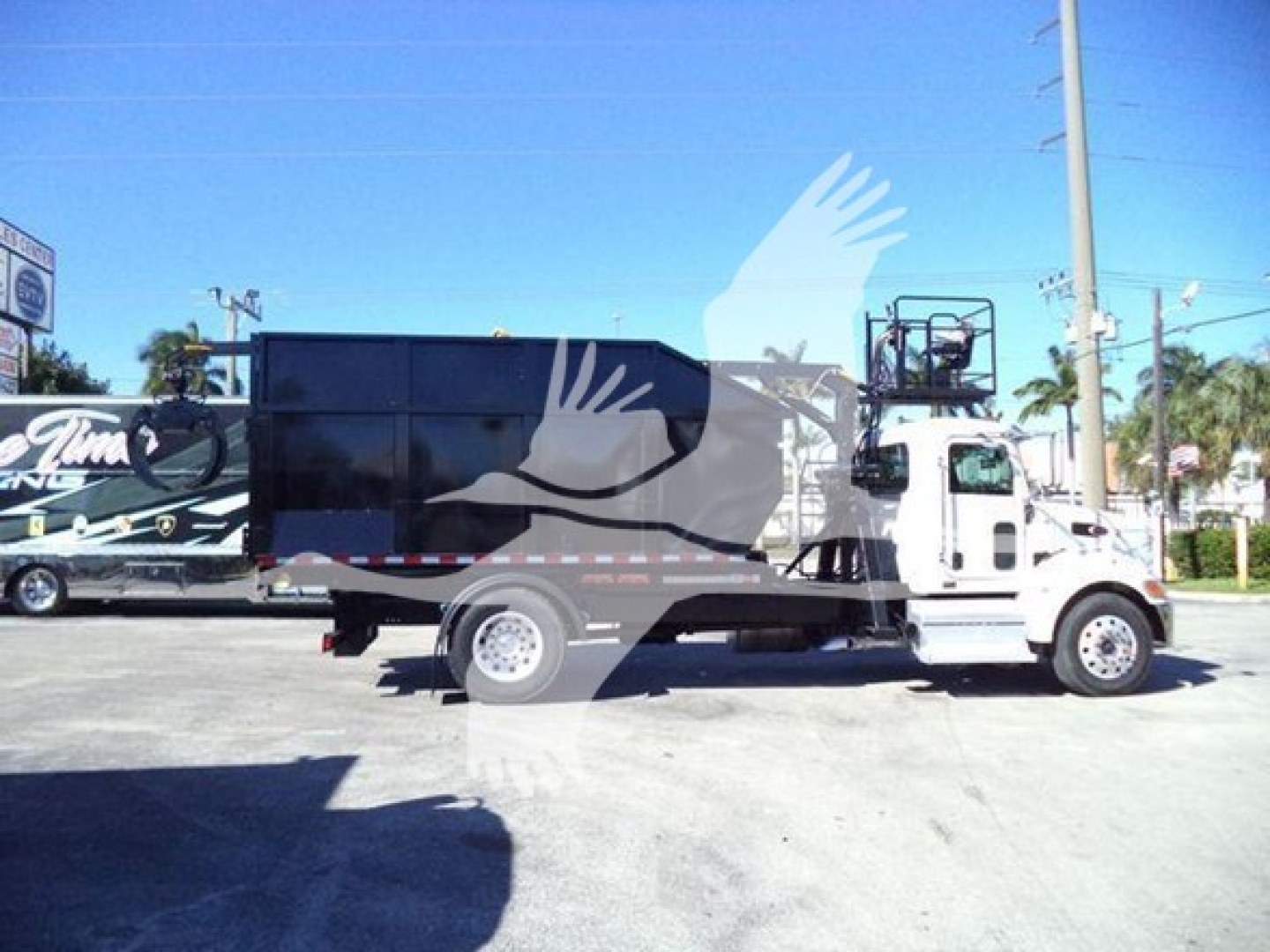 Peterbilt 337 roll-off truck in side view showing cargo bed and cab with white chassis