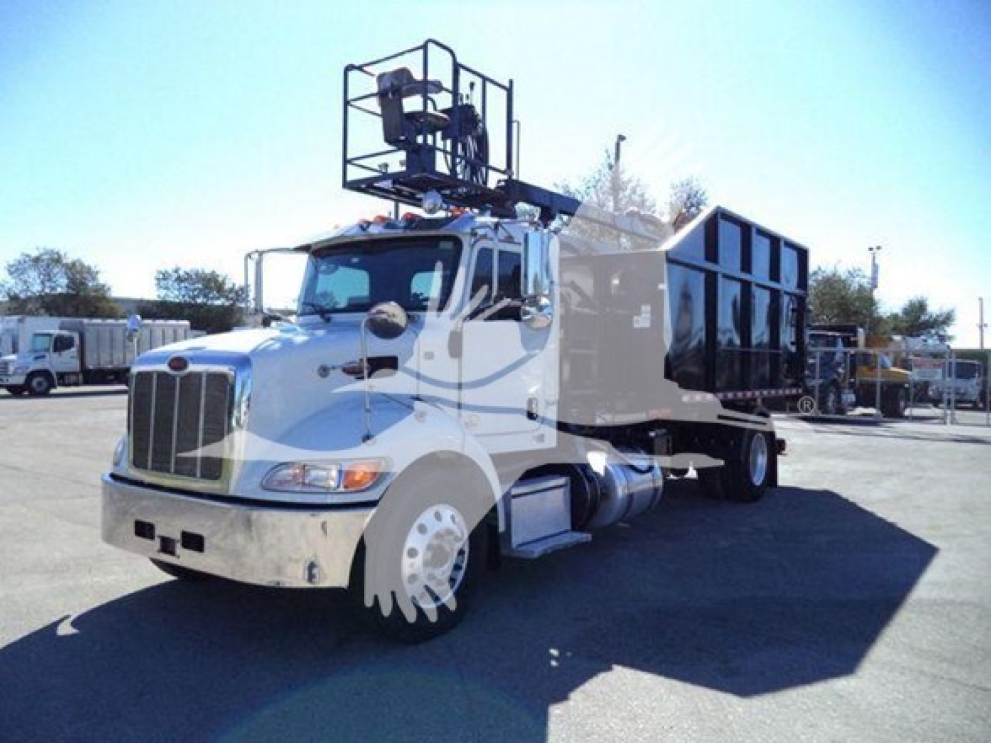 Peterbilt 337 roll-off truck showing cab and black dumping hopper with rear access and equipment rack on top.