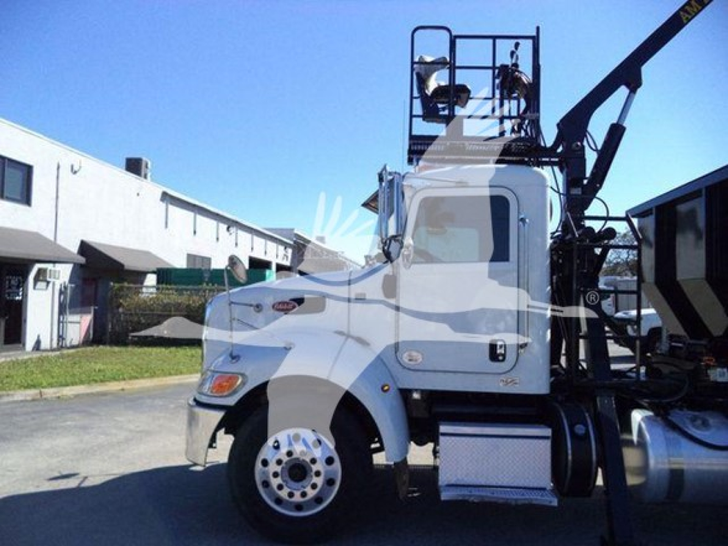 Peterbilt 337 roll-off truck side view showing cab, front wheel, steps, and lifting apparatus.