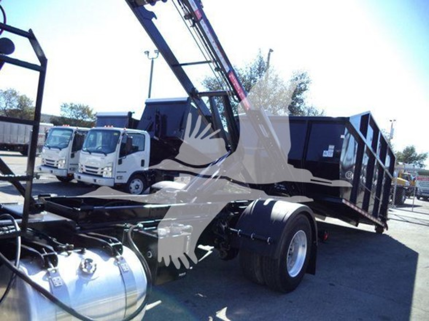 Peterbilt 337 roll-off truck in-service, side view showing cab and trailer with hydraulic crane and large black dumpster container.
