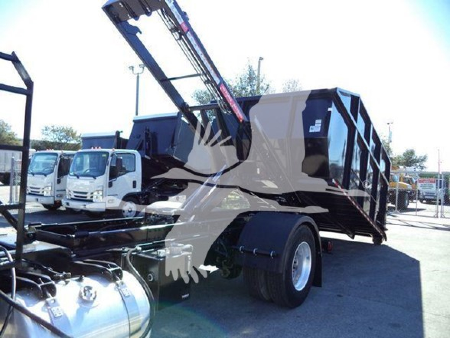 Peterbilt 337 roll-off truck with crane hoist and large dump body in yard; side view showing rear dual wheels and hydraulic components.